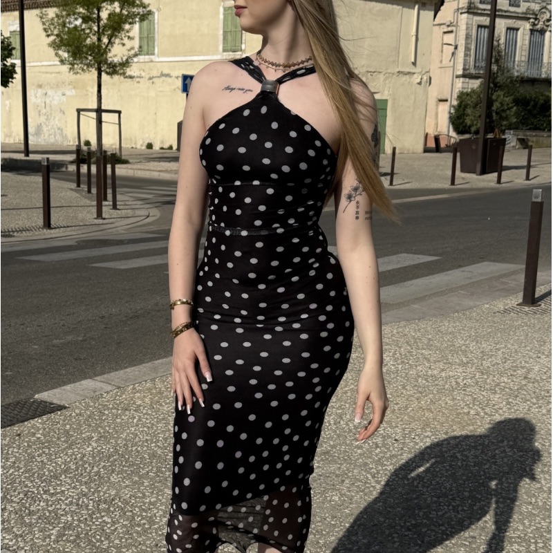Femme en robe noire à pois ajustée, look féminin et élégant en extérieur