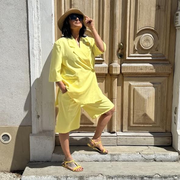 Silhouette féminine en tenue jaune devant une porte en bois, ambiance élégante et solaire