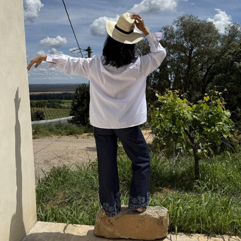 Femme en chemise blanche et chapeau face un un paysage naturel, ambiance libre et ensoleillée
