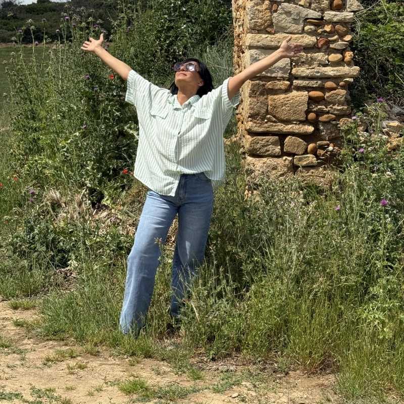 Femme en chemise rayée et jean dans la nature, ambiance joyeuse et naturelle
