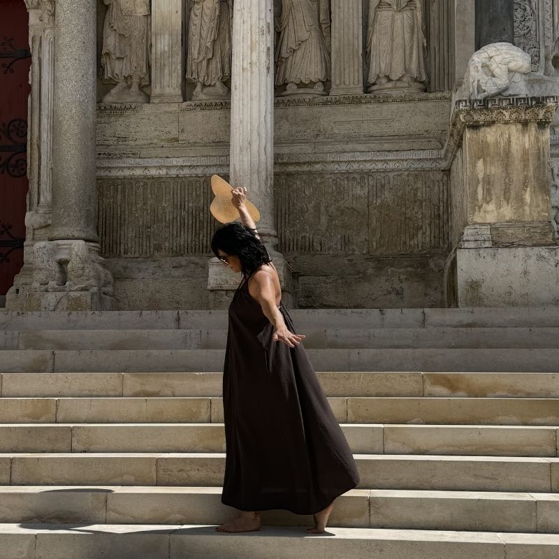 Femme en robe longue marron devant l'abbatiale de Saint -architecture en pierre et ambiance élégante