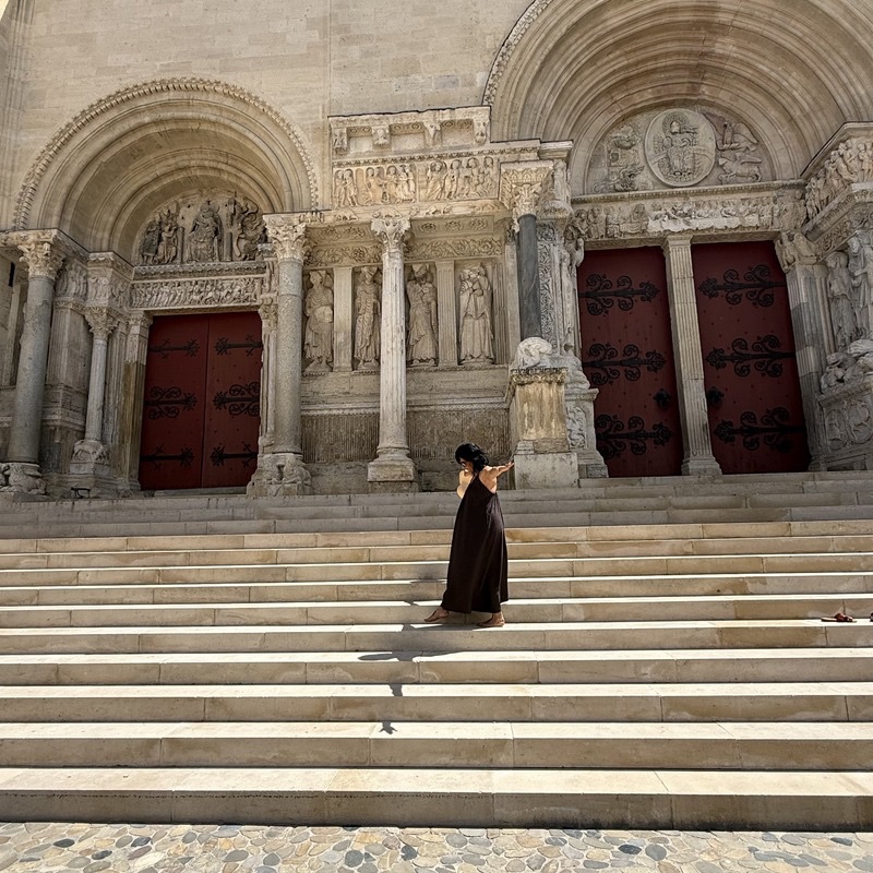 Femme en robe élégante devant l'abbatiale de Saint-Gilles boutique Paris Tenue service client et questions fréquentes