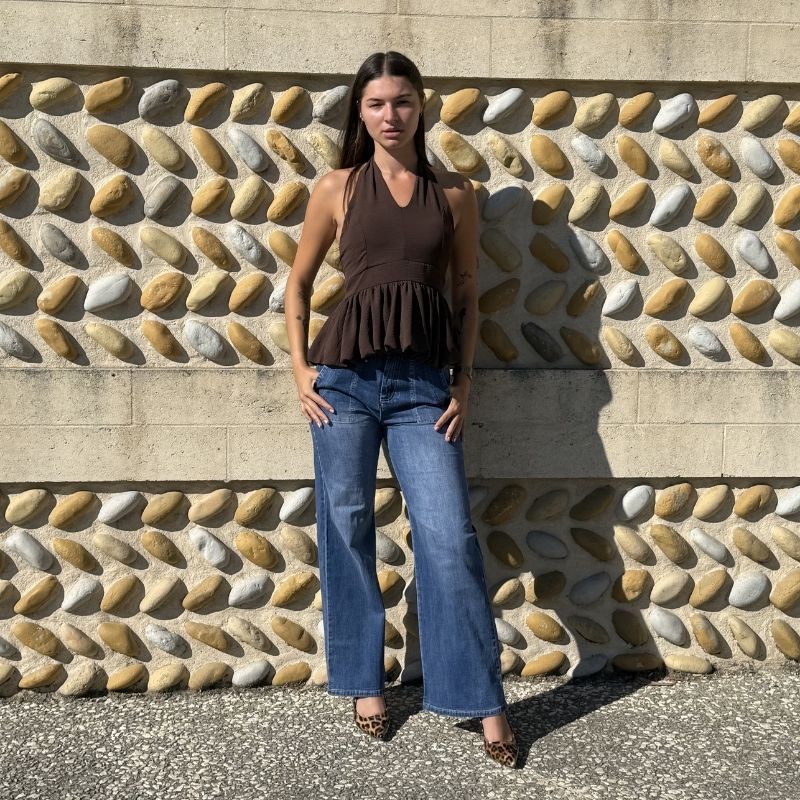 Femme portant un jean bootcut bleu taille haute avec coupe évasée, vue de face.