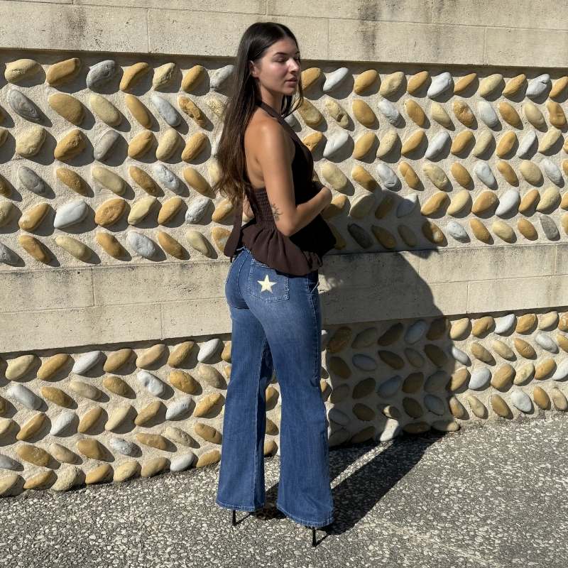 Vue arrière d'un jean bootcut bleu taille haute avec étoiles blanches sur les poches arrière.