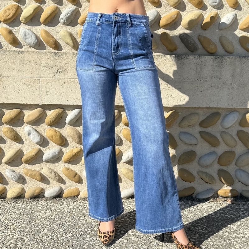 Gros plan sur le devant d'un jean bootcut bleu taille haute avec jambes évasées et denim délavé.